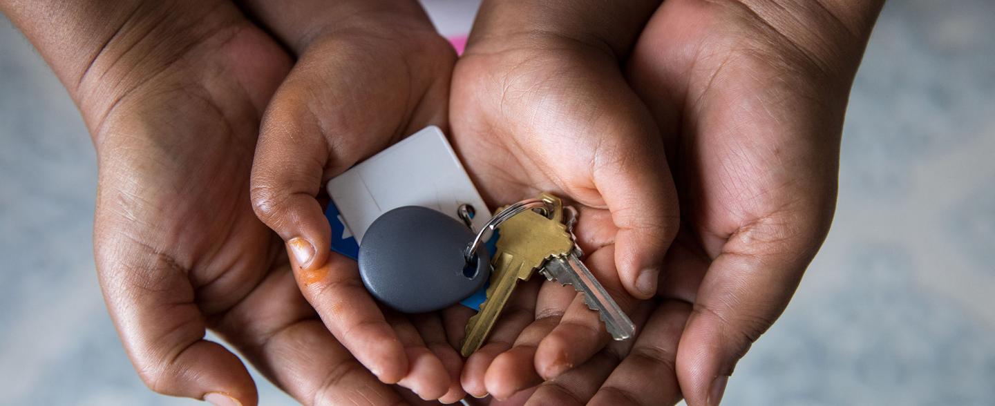 A Black mother's hands cradle child hands with house keys
